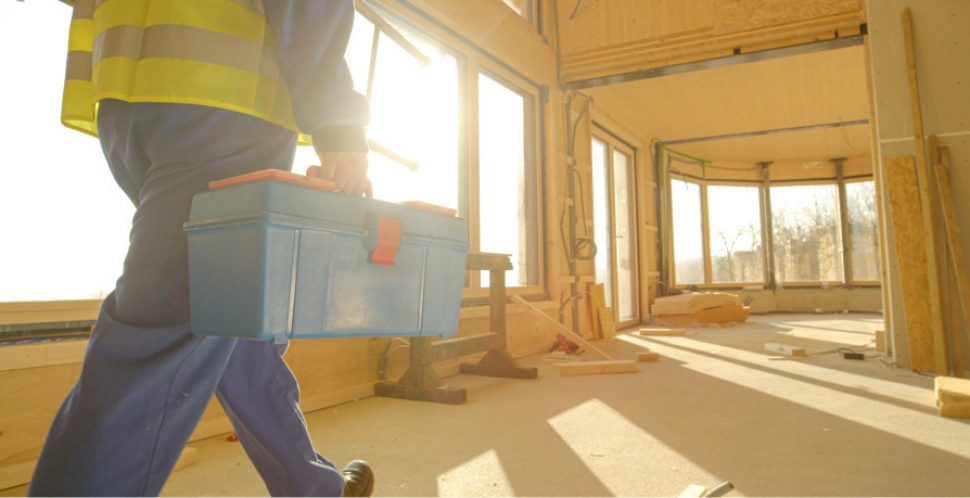 A construction worker walks with a tool box in a retrofit construction project