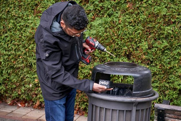 A city worker installs a Pello smart sensors to public realm garbage and recycling bins across Vancouver to track fill rates and service patterns