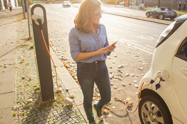 A woman plugs in her electric vehicles for charging in clean greenest city Vancouver
