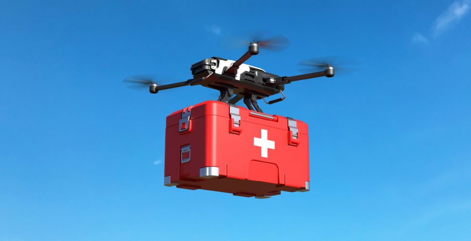 A drone carries a red first aid package with the blue sky in the background, an example of Advanced Air Mobility in Vancouver